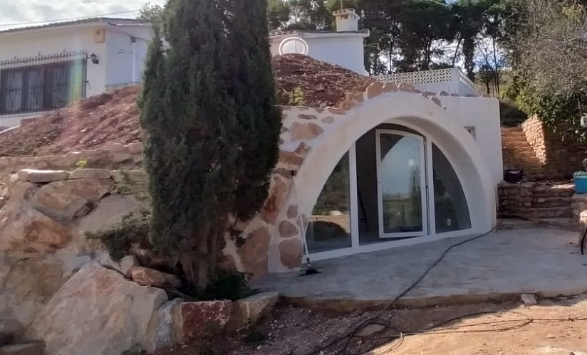 Domo semi-enterrado SolDomo integrado en roca natural — arquitectura monolítica ecológica